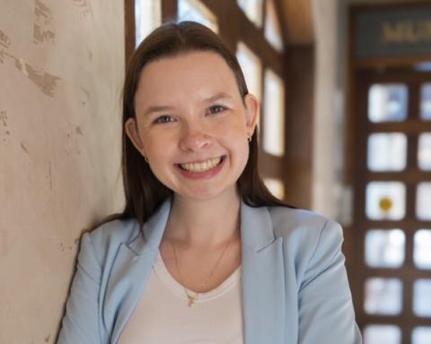 Katie is standing in front of doors with sunlight coming through